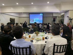 Conference room with attendees at round tables during Media Outlook 2023 presentation